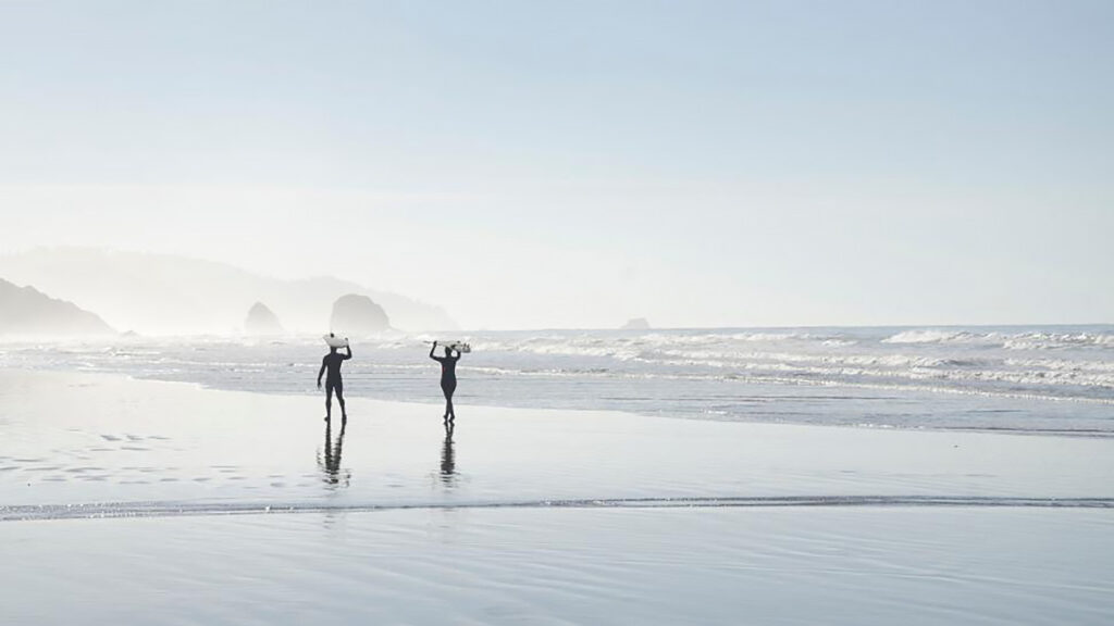 ビーチを歩く二人のサーファー