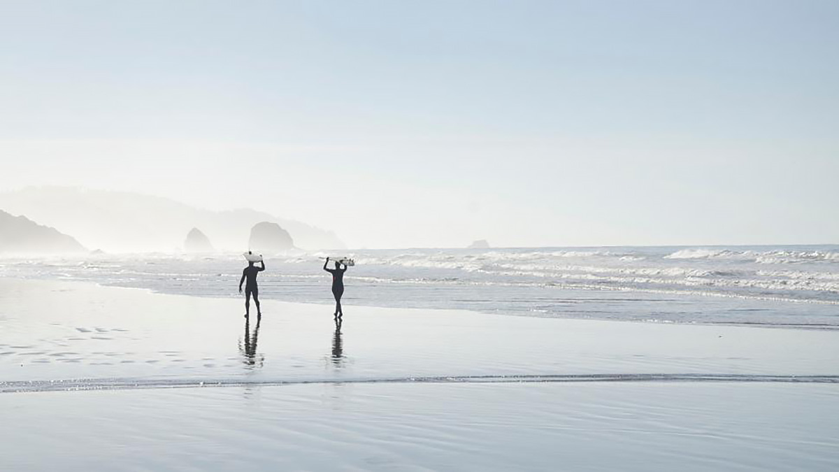 ビーチを歩く二人のサーファー